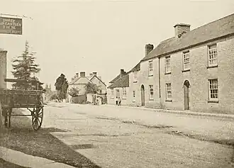 1906 photograph of a village high street showing a two-storey stone house