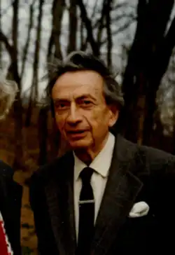 An older man in a suit standing in an autumn wood