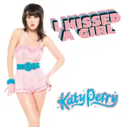 Katy Perry in a pink and blue one-piece outfit looks at the camera with her eyes wide and mouth slightly open.