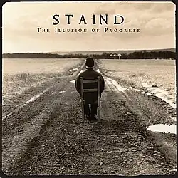 A photo of a young man, viewed from the back, sitting in a chair on the road with no cars passing by. The band's name and the album title is written above in black.