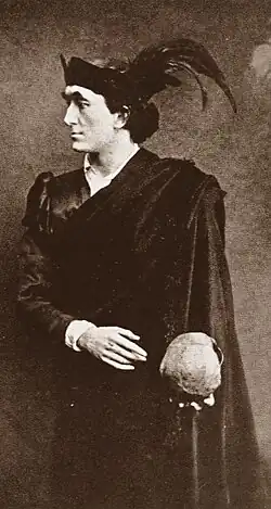 clean-shaven white man in black Renaissance costume, holding a skull