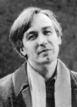 A middle-aged man in a collared jacket with an unwrapped scarf
