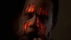 A man feels the flesh off of his face to reveal fire underneath.