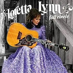photo of Loretta Lynn in light purple dress playing guitar on porch steps