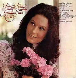 photo of Loretta Lynn leaning on column with pink flowers