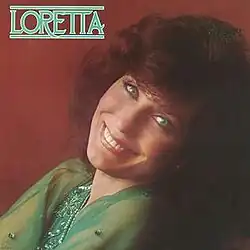 smiling photo of Loretta Lynn in green with red background