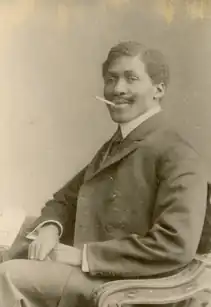 Mandenga Diek wearing an elegant suit, with an upturned cigarette