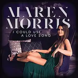 An image of a long brown-haired woman in a green dress sitting on a purple loveseat.