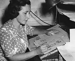 Black-and-white phot of a woman drawing at a drawing board