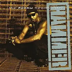A sepia tone image of a man squatting down with his hands clasped, wearing a black toque, sunglasses, tank top, pants and shoes. The album title appears above him colored in white, and the artist's logo appears beside him sideways, colored in grey.