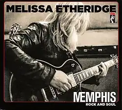 A black-and-white photo of Etheridge playing guitar