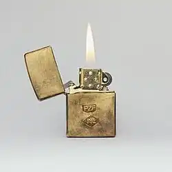 A golden Zippo lighter burns on an off-white background.