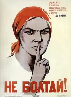 A woman who wears a red headscarf in the centre makes a shushing action.