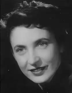 Black and white, three-quarter profile, glamour, 1940s-style, studio portrait of a smiling young woman with short, dark, curly hair