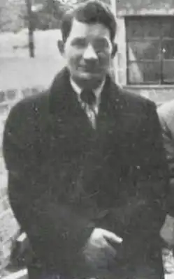Photograph of Peter Tyrrell, a man with short dark hair wearing a dark coat and smiling with his mouth closed