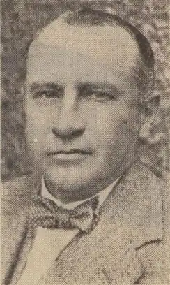 A man wearing a jacket, white shirt, and dotted bow-tie.