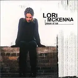 photo of Lori McKenna thinking seated on brick wall in front of window