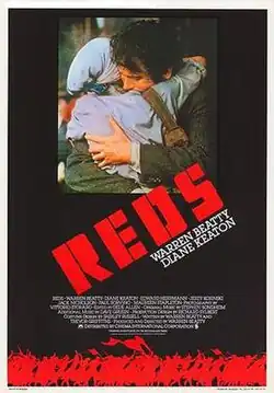 A dark poster with man and woman embracing tightly at the center, with the bold red title REDS slanted across the bottom