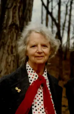 An elderly lady in a polka dot shirt, a suit jacket, and a red ascot