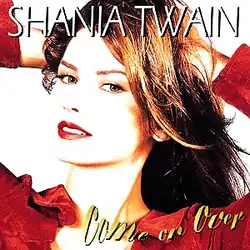 Photograph of a woman standing in front of a white background. She is wearing a red shirt and holding her hands in her hair, with her mouth ajar. The words SHANIA TWAIN are written at the top of the image in white capital letters. The words Come on Over are written at the bottom of the image in yellow cursive-style letters.