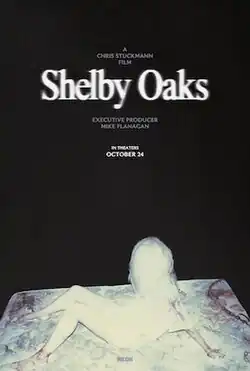 A woman whose face is blurred by overexposed light lies on a blood stained mattress with a chain