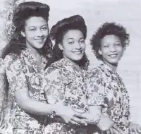 three young adult black women, who look alike apart from their age differences, in identical dresses