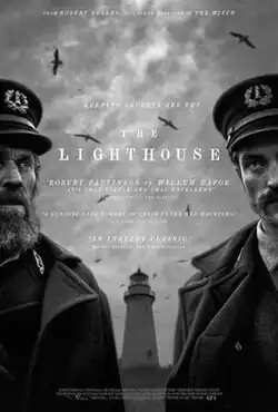 Two lighthouse keepers, one old and one young, stand in front of a lighthouse with stern looks as seagulls fly overhead.