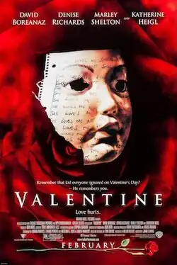 A white mask, made out notebook paper scribbled repeatedly with "SHE LOVES ME" and "SHE LOVES ME NOT", against the background of a dark red rose.
