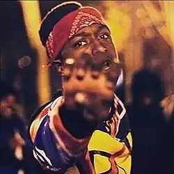 Young man in a hoodie rapping into the camera in a city street.