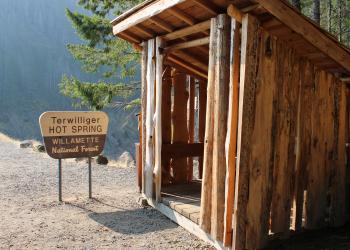 A sign that says "terwilliger hot springs" next to a wooden shelter.